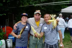 Three men making silly faces holding corn on the cob