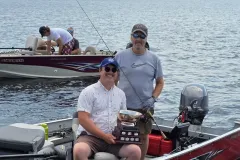Mark Ristow and Patrick Robertson hold the fishing trophy in their boat on Percy Lake.