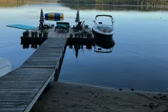 The floating dock and ramp from the shore, with a boat moored alongside on a calm lake