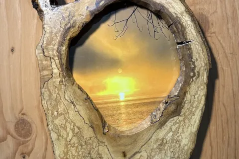 A photo of the sun rising over Percy Lake, set in a hollowed-out, polished tree-trunk frame