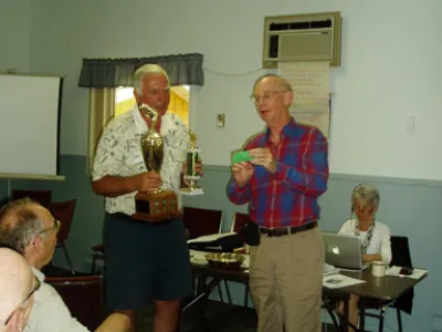 Harry Winder receiving the fishing trophy at the AGM (on behalf of his grandson) and Joe Matys presenting a special lure