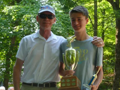 Dillon holding the youth fishing trophy with a man's arm around him