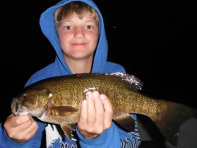 Leadro holding up a fish in the boat at dusk