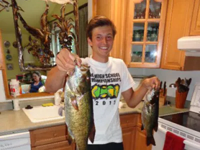 Chris standing in the kitchen holding a fish in each hand