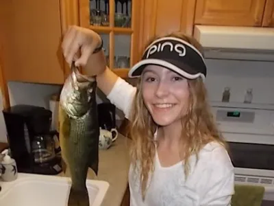 Sophia holding a fish above a kitchen sink