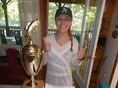 Sophia standing beside a big shiny trophy and her winning lake trout