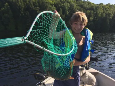 Julian Tilman holding a net with a fish inside while sitting in a canoe