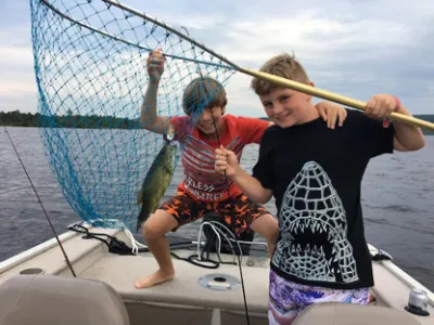 Julian and friend holding up a net with a fish inside