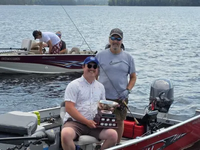 Mark Ristow and Patrick Robertson hold the fishing trophy in their boat on Percy Lake.