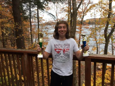 Julian Tilman holds up to plastic trophies on the deck of his family's cottage.