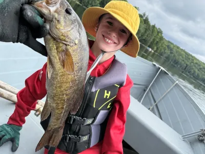 A young Arlo poses with a bass while sitting in a boat.