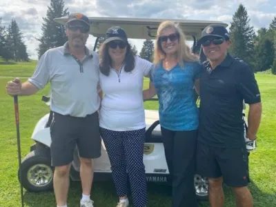 The team of Mark, Karen, Teresa, and Rob gather in front of a golf cart.
