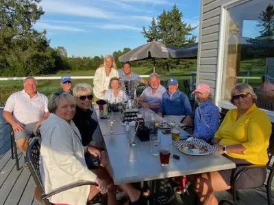 A group of golfers enjoy dinner on a patio.