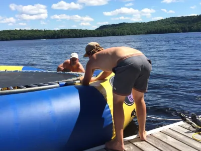 Climbing onto the blue and yellow water trampoline from the dock