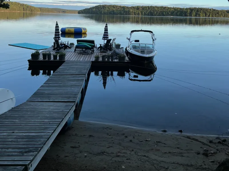 The floating dock and ramp from the shore, with a boat moored alongside on a calm lake